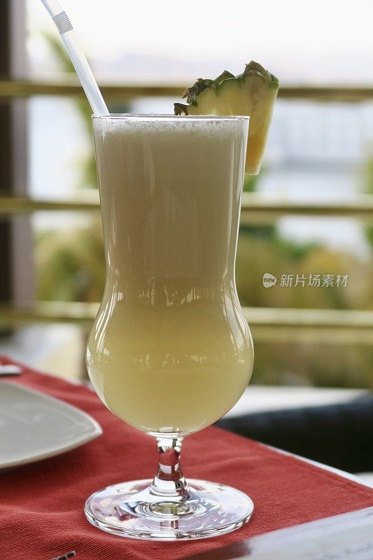“Piña colada”酒精鸡尾酒/鸡尾酒饮料在节日的飓风杯与菠萝装饰和稻草，印度酒吧背景照片